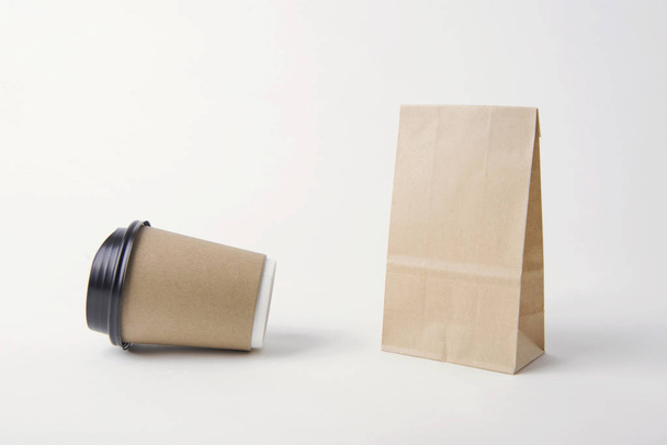 Bolsa de papel marrón en blanco y taza de café para la plantilla de maqueta de publicidad y fondo de marca
.  - Foto, Imagen