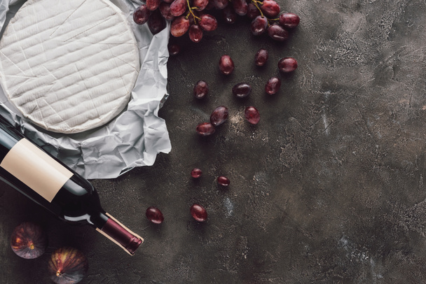 vista dall'alto di bottiglia di vino, brie cheese, fichi e uva su superficie scura
 - Foto, immagini