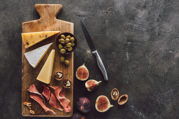 flat lay with assorted cheese, jamon and figs on dark surface - Photo, Image