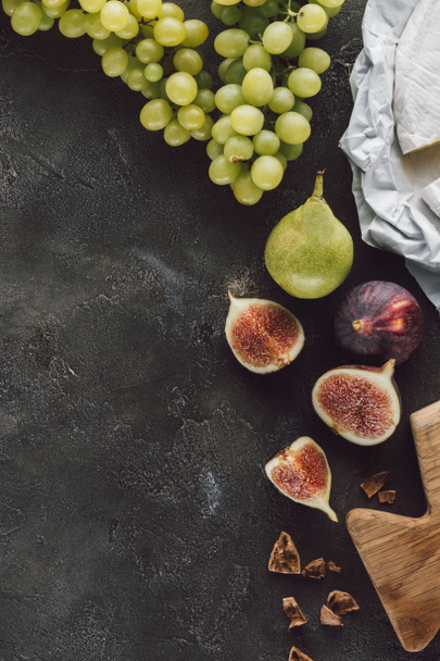 flat lay with arranged figs, grape and cheese on dark surface - Photo, Image