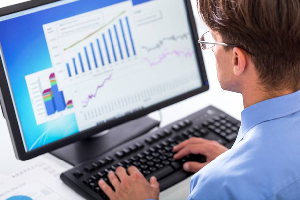 Portret van een zakenman analyseren van grafieken en diagrammen op Computer-monitoren - Foto, afbeelding