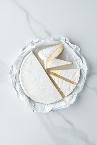 bovenaanzicht van brie kaas op witte marmeren tafelblad - Foto, afbeelding