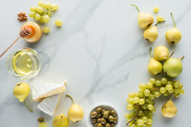 flat lay with camembert cheese, wine and fruits on white marble surface - Photo, Image