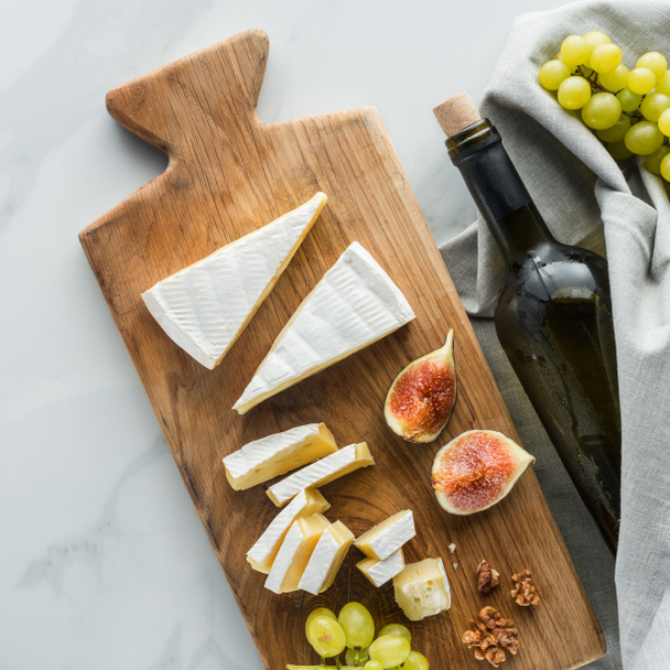 camembert peyniri kesme tahtası üzerinde gıda kompozisyonu ile yat ve beyaz mermer yüzey üzerinde şarap - Fotoğraf, Görsel