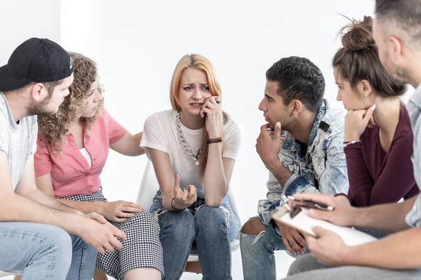 Young people supporting crying teenage girl during meeting with therapist - 写真・画像