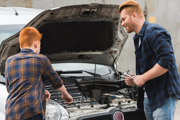 ginger hair father and son repairing car with open hood - Foto, Bild