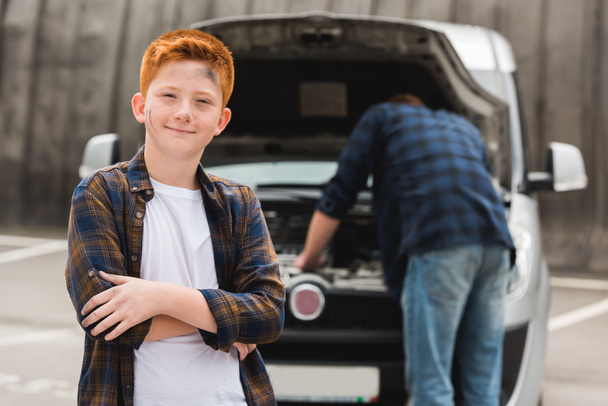 father repairing car with open hood, son looking at camera - Photo, Image