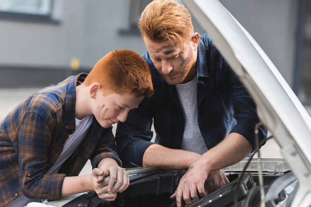 Isä ja poika korjaamassa autoa ja etsimässä avohuppua
 - Valokuva, kuva