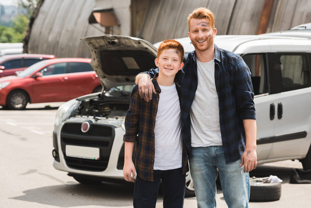 happy father hugging son after repairing car and they looking at camera - Foto, Bild