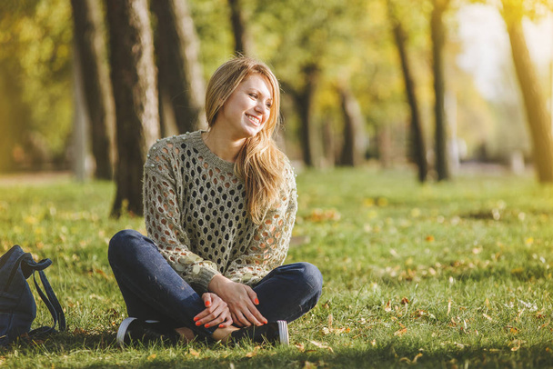 blonde est assise sur l'herbe verte dans le parc
 - Photo, image
