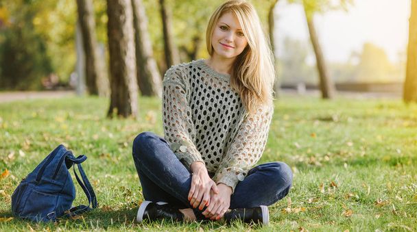 siedzi blondynka na zielonej trawie w parku - Zdjęcie, obraz