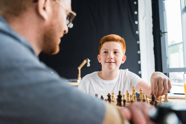 father and son playing chess and looking at each other at home - Photo, Image