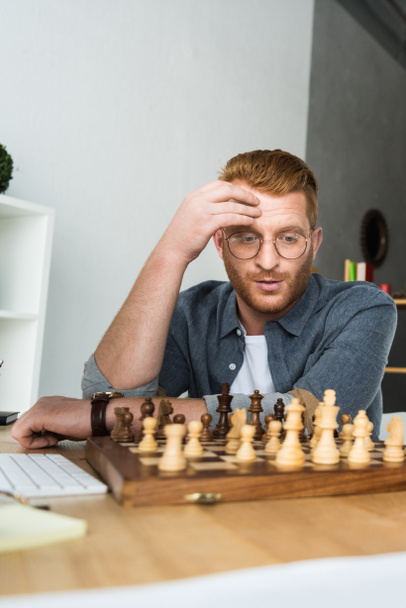 handsome pensive man looking at chessboard at home - Fotoğraf, Görsel