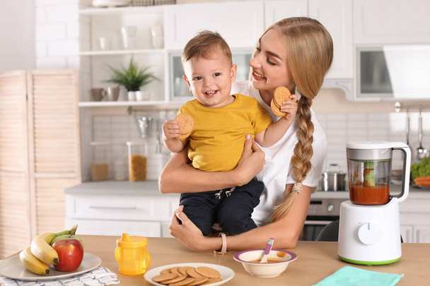 Woman feeding her child in kitchen. Healthy baby food - Zdjęcie, obraz