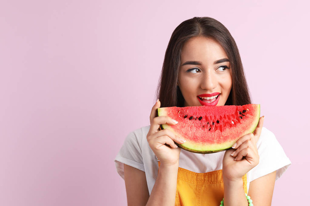 Beautiful young woman posing with watermelon on color background - Foto, Bild