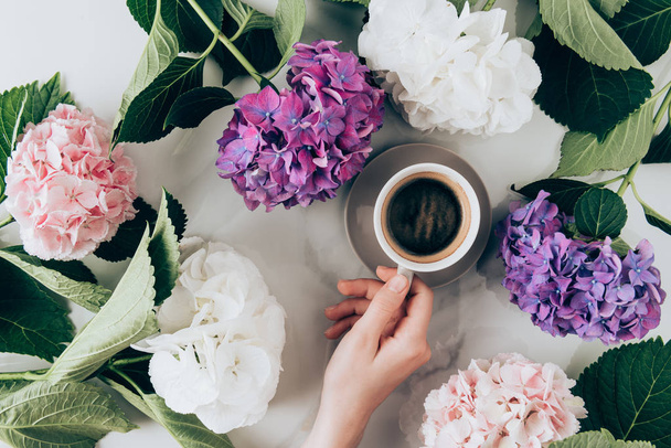 flat lay with hortensia flowers and female hand with cup of espresso coffee - Photo, Image