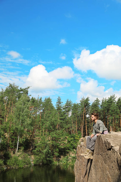 Young man on rock near lake and forest. Camping season - Fotografie, Obrázek