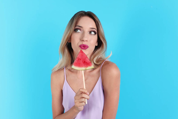 Pretty young woman with juicy watermelon on color background - 写真・画像