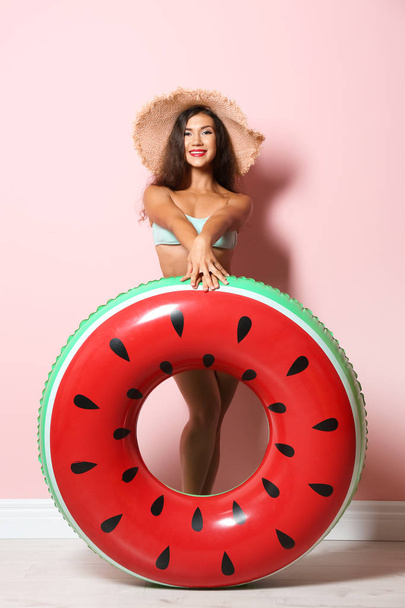 Beautiful young woman with inflatable ring near color wall - Foto, Imagem