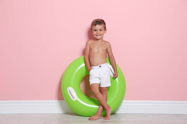 Cute little boy with bright inflatable ring near color wall - Фото, зображення