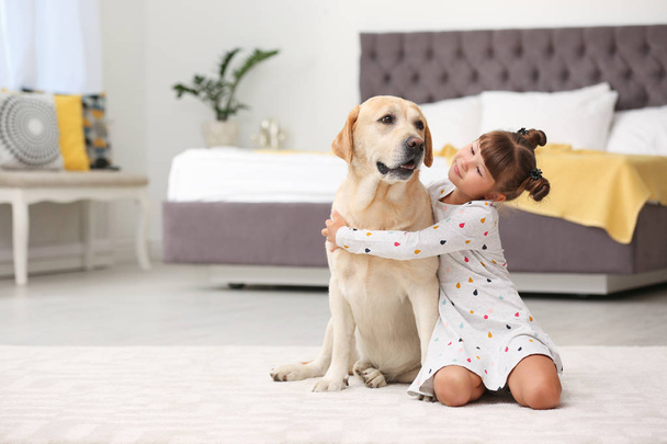 Adorable yellow labrador retriever and little girl at home - Foto, Imagen