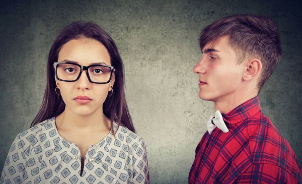 Joven mujer seria en gafas mirando a la cámara mientras está de pie con el hombre que tiene fecha y tomar la decisión
 - Foto, Imagen