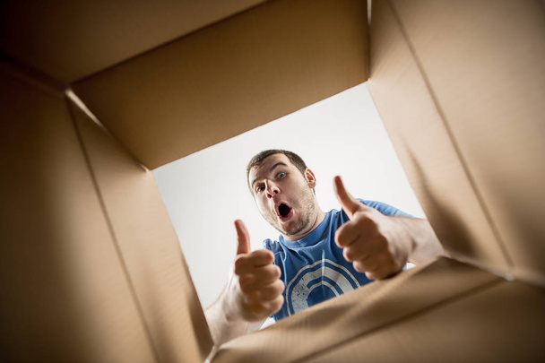 Man unpacking and opening carton box and looking inside - Photo, image