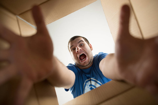 Man unpacking and opening carton box and looking inside - 写真・画像