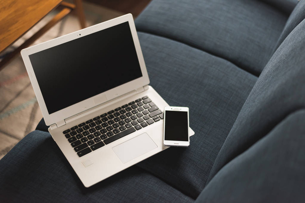 laptop i smartphone na kanapie z nikt, pojęcie pracy w domu - Zdjęcie, obraz