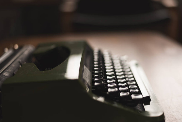 Винтажная пишущая машинка зеленого цвета на столе
 - Фото, изображение