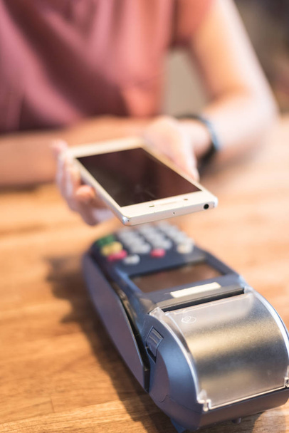 женщина, платящая с помощью технологии NFC с помощью смартфона
 - Фото, изображение