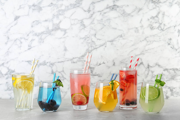 Glasses with lemonades on table against marble background - Photo, Image