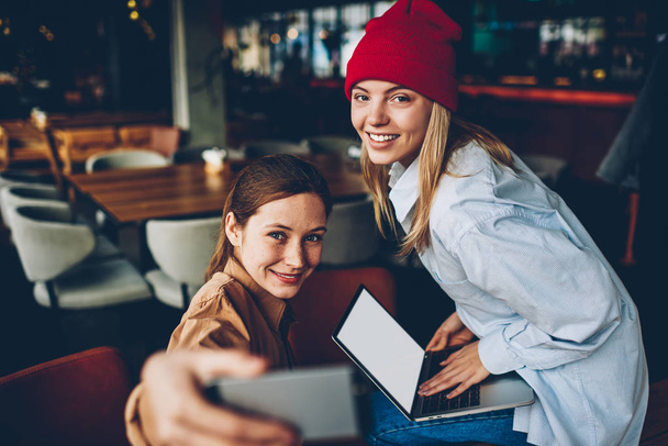 Портрет щасливих дівчат-гіпстерів, одягнених у повсякденне вбрання, посміхаючись на камеру, оновлюючи програму на сучасному ноутбуці з порожньою зоною екрану, підключеною до бездротового Інтернету 4G
 - Фото, зображення