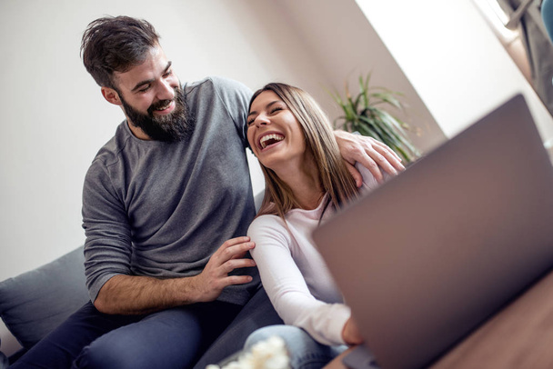 Boldog a fiatal pár ül a kanapén, használ laptop részére online bevásárlás-on nappali. - Fotó, kép