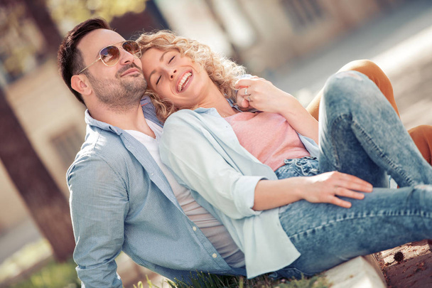 Feliz joven pareja enamorada sentada abrazada en la calle
 - Foto, imagen
