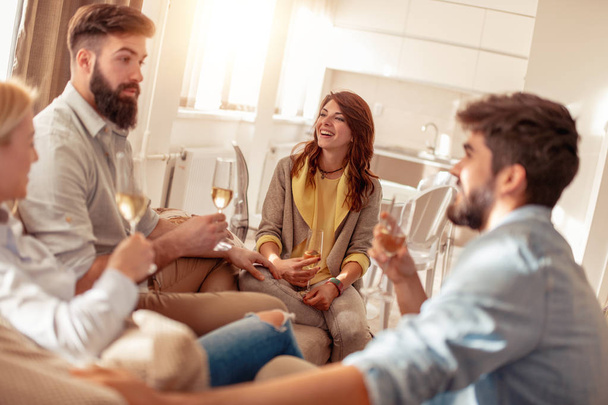 Друзі чудово проводять час вдома, п'ють вино
. - Фото, зображення