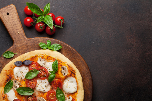 Italiaanse pizza met tomaten, mozzarella en basilicum. Bovenaanzicht met ruimte voor uw tekst - Foto, afbeelding