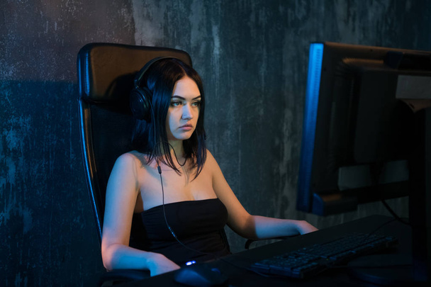 Gamer tyttö istuu mukava tuoli tietokoneella ja pelaa videopelejä. Nuori nainen lepää kotona tietokonepeleissä
. - Valokuva, kuva