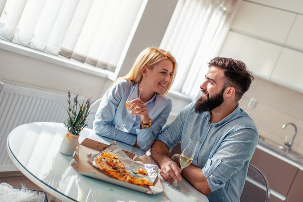 Young couple having great time at home,eating pizza and drinking wine. - Photo, Image