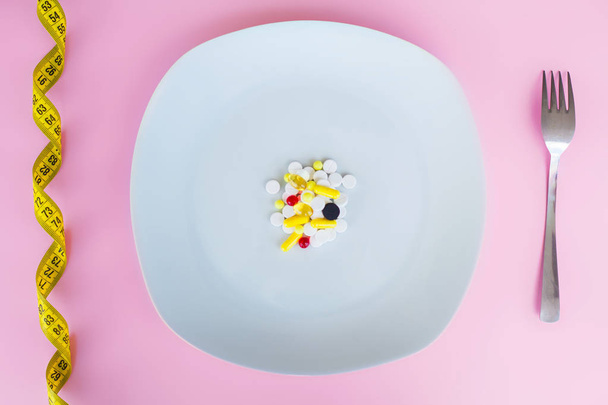 Ιατρική αντίληψη. Χρωματιστά χάπια και κάψουλα στο πιάτο με πιρούνι. Φαρμακείο θέμα, καψάκιο χάπια με αντιβιοτικό φάρμακο στα πακέτα. - Φωτογραφία, εικόνα