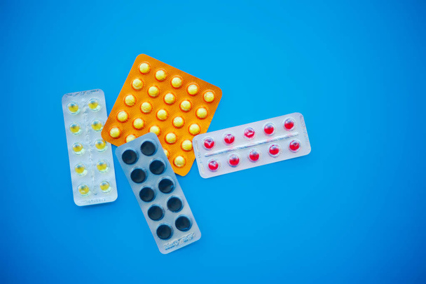 Medische pillen. Gekleurde pillen en capsules op blauwe achtergrond. Apotheek thema, Capsule pillen met geneeskunde antibioticum in pakketten. - Foto, afbeelding