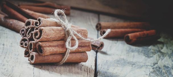Cinnamon sticks tied with jute rope on old wooden background - Fotó, kép