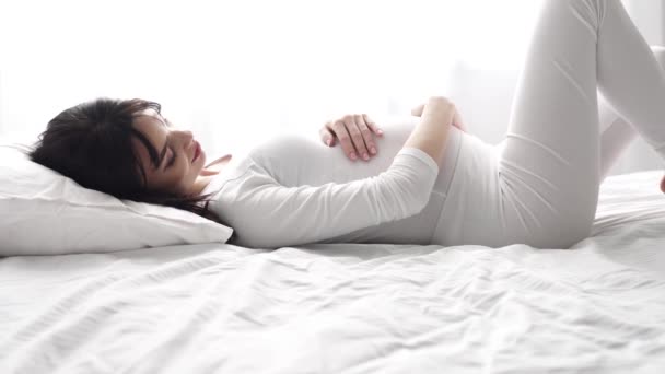 Pregnant Beautiful Woman Lying On Bed And Caressing Baby Belly - Video, Çekim