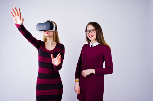 Two girls in purple dresses trying out virtual reality glasses in the studio. - Photo, Image