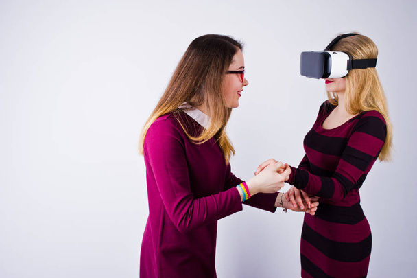 Две девушки в фиолетовых платьях примеряют очки виртуальной реальности в студии
. - Фото, изображение