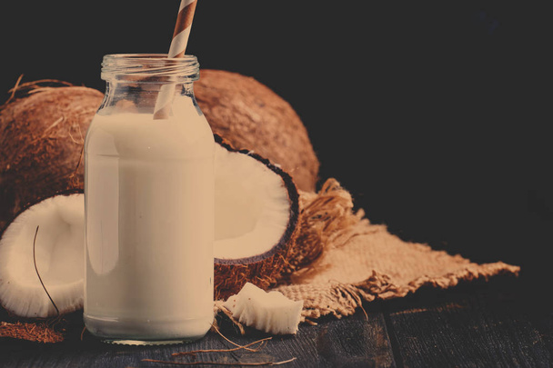 Coconut milk in a glass bottle, dark background - 写真・画像
