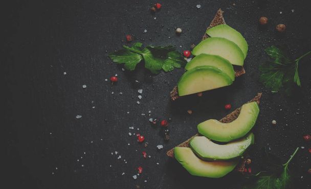 Sandwiches with avocado and spices on a black stone background - Foto, imagen