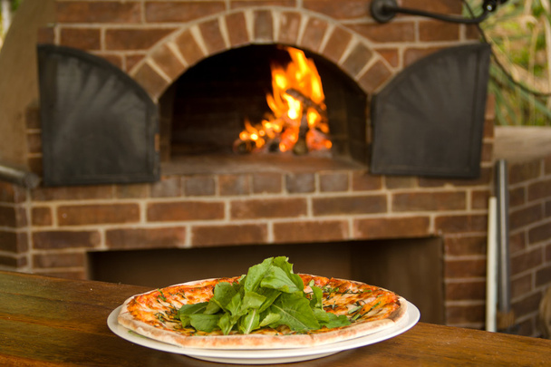 バック グラウンドでピザのオーブンでプレート上のピザ - 写真・画像