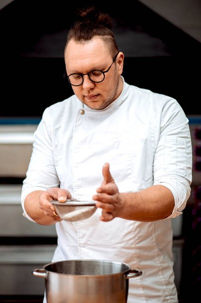 Um homem chef prepara cupcakes na cozinha
 - Foto, Imagem