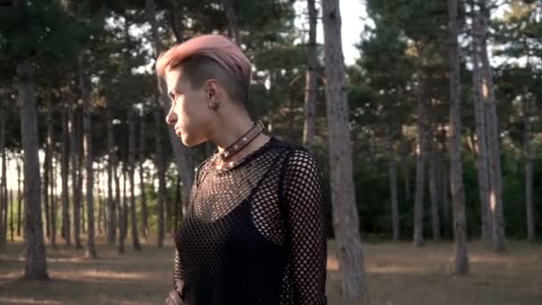 Young Pretty Punk Girl in Collar and Net. Pink Hair Girl walking in Pine Forest at Sunset Time - Filmagem, Vídeo